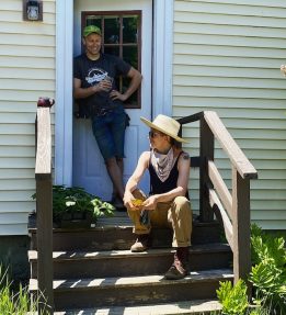 Farthest Field Farm A person sitting on a front porch stoop as someone stands in the doorway behind them