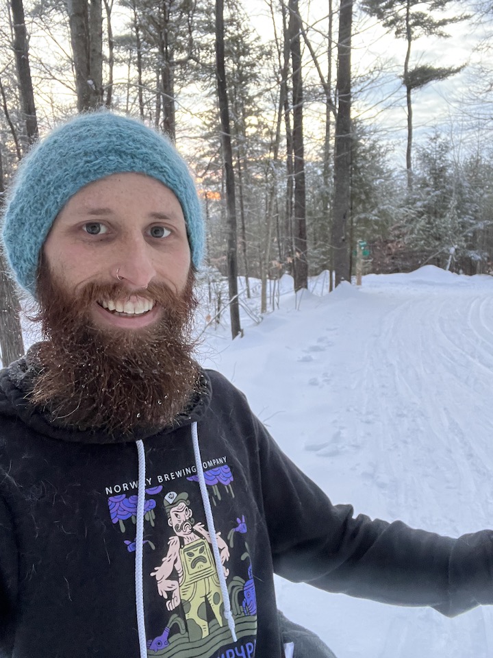 MOFGA Volunteer Daniel Sipe stands in the snow-covered woods.